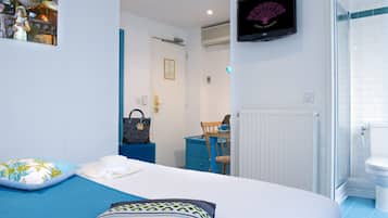 Un dormitorio con cama, televisor, escritorio y baño.