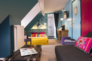 A bedroom with a bed, a desk, a chair, and a suitcase.