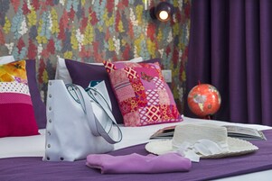 A neatly arranged bed with colorful pillows, a globe, and a stack of books.