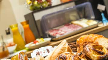 Un bufé de desayuno con pasteles, frutas y bebidas.