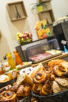 A breakfast buffet with pastries, fruits, and beverages.