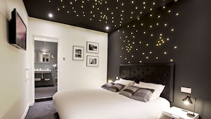 Un dormitorio con una cama grande, una mesita de noche y un televisor instalado en la pared.