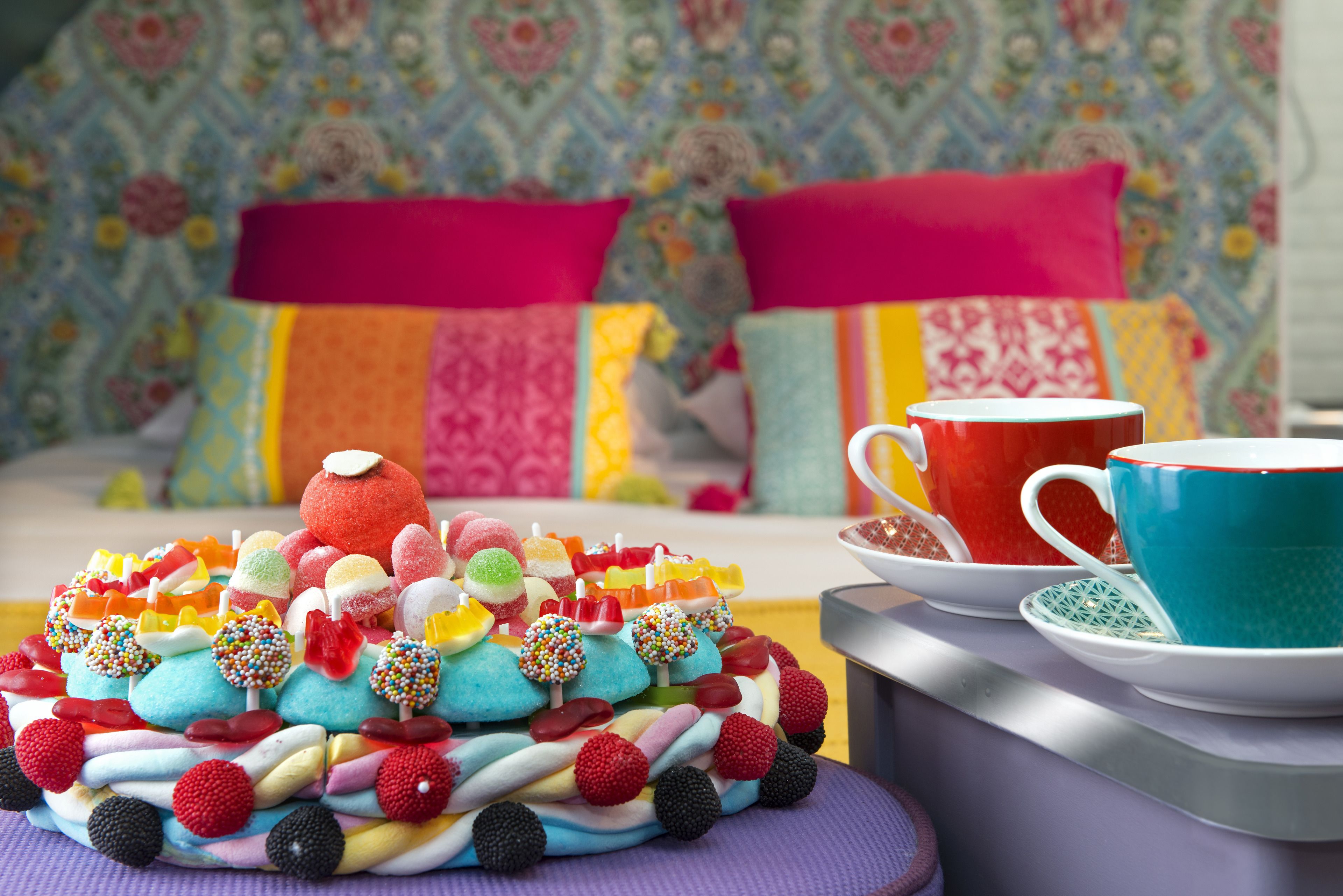 Une table où sont présentés de nombreux desserts colorés, ainsi qu’une tasse et une soucoupe.