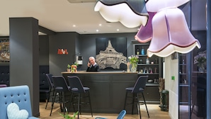 Un interior moderno con mostrador de recepción, zona de bar, asientos y elementos decorativos.