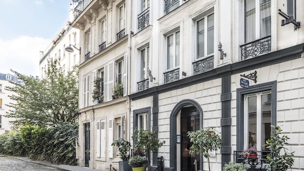 Un edificio histórico con varios balcones, grandes ventanales y una calle adoquinada.