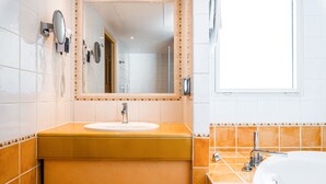 A bathroom with a sink, mirror, and a large bathtub.