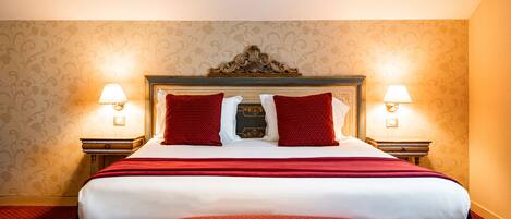 A hotel room with a large bed, two bedside lamps, and a decorative headboard.