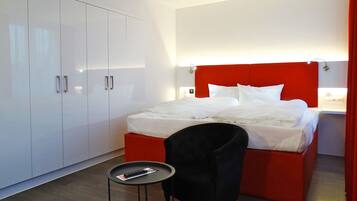 A hotel room with a bed, a small table, a chair, and a wardrobe.