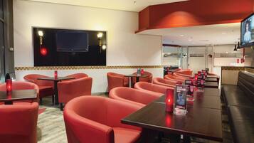 A restaurant with red seating, a TV mounted on the wall, and a counter with a menu.