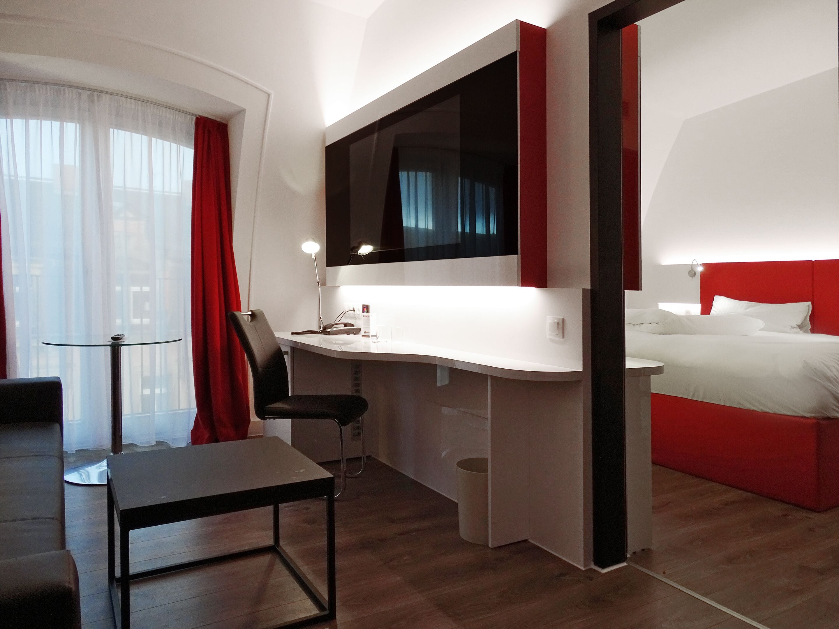 A modern hotel room with a desk, chair, and bed.