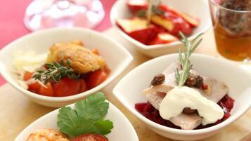 A table with four bowls of food, a glass of red wine, and a glass of tea.
