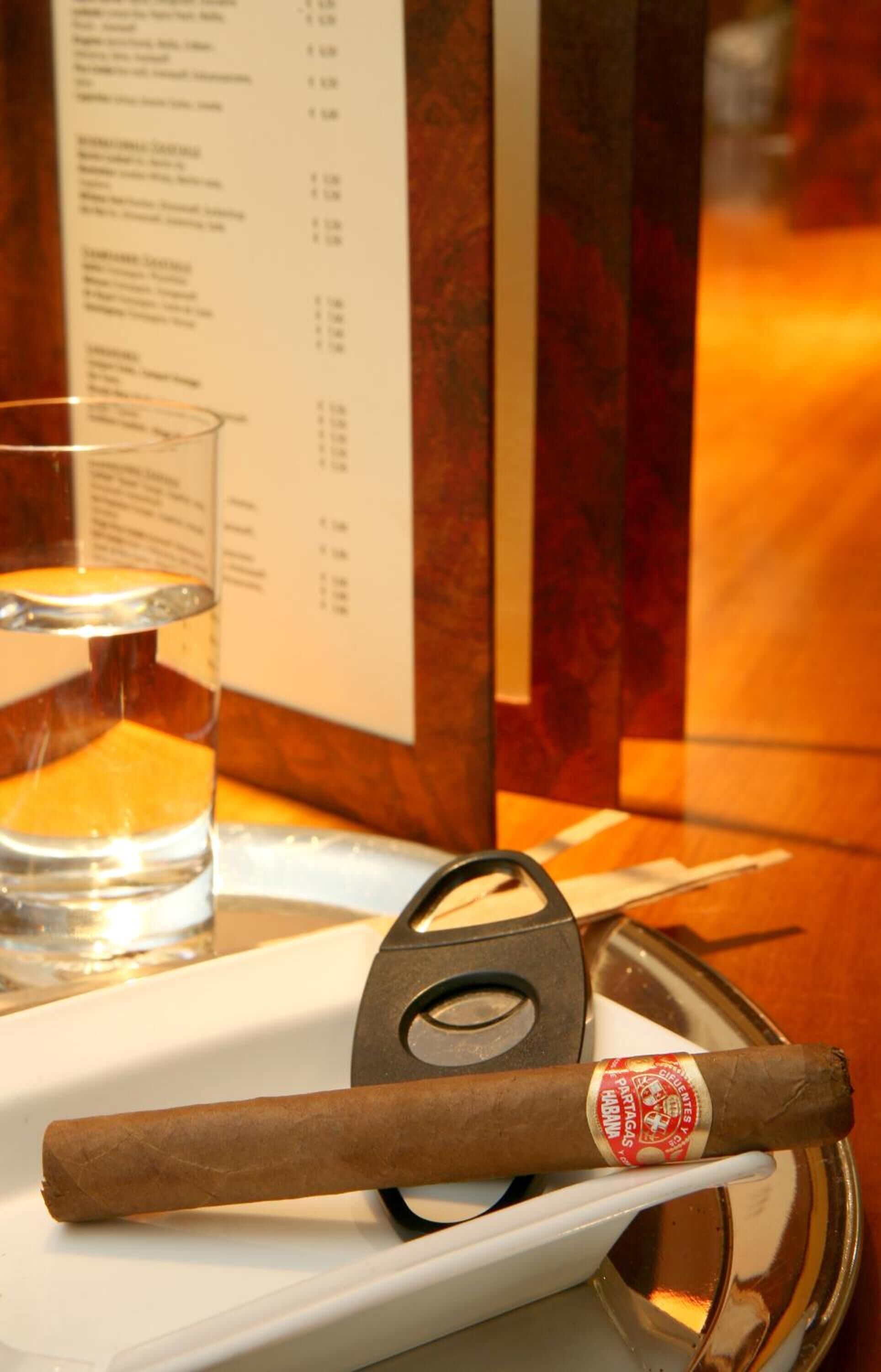 A cigar on a tray with a menu in the background.