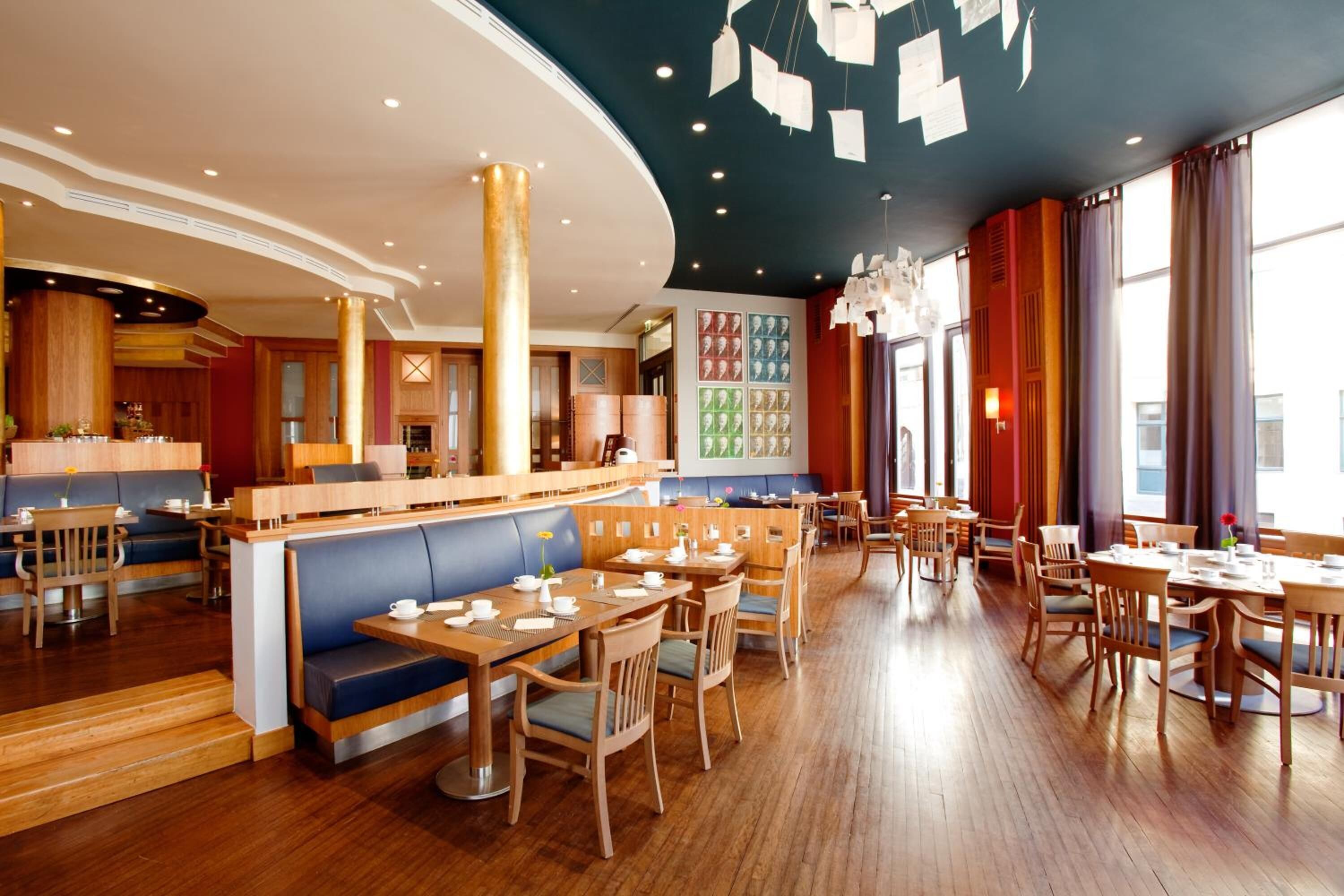 A modern restaurant with wooden furniture, a curved ceiling, and a wall with a grid of images.