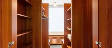 A walk-in closet with wooden shelving, a bench, and a ceiling light.