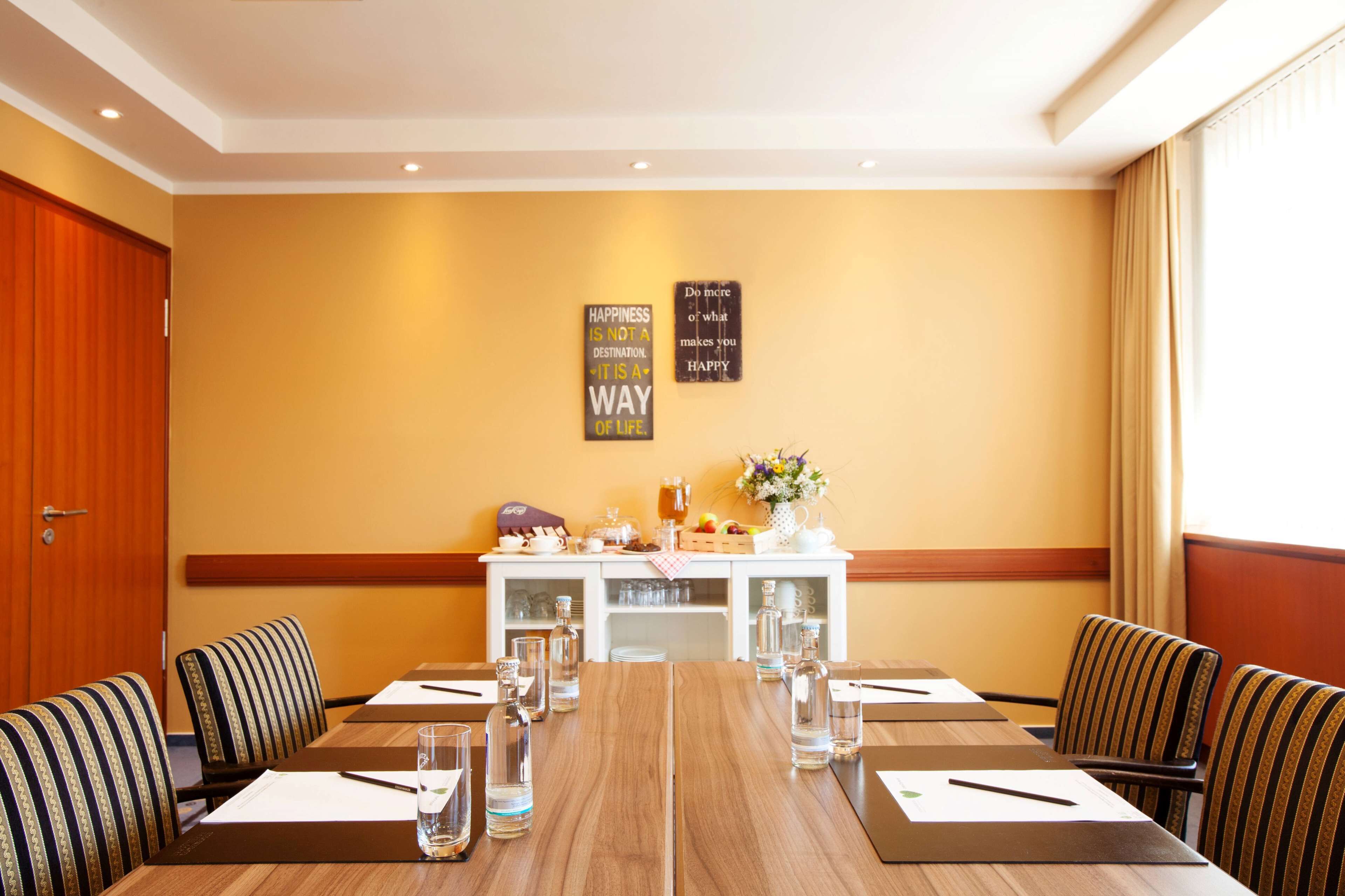 A conference room with a long table, chairs, and a white cabinet with various items.