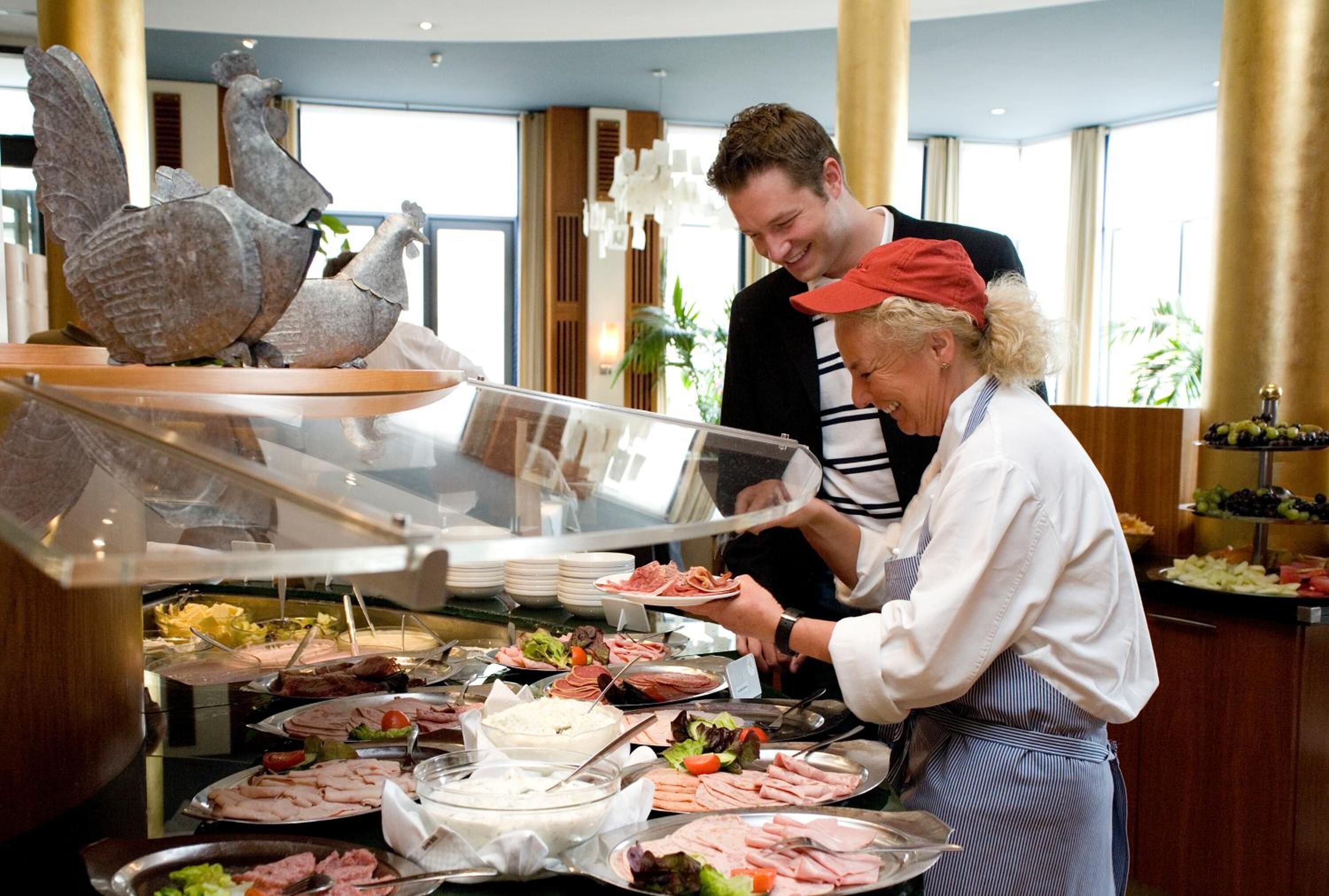 A buffet setup with various food items and a decorative rooster statue.