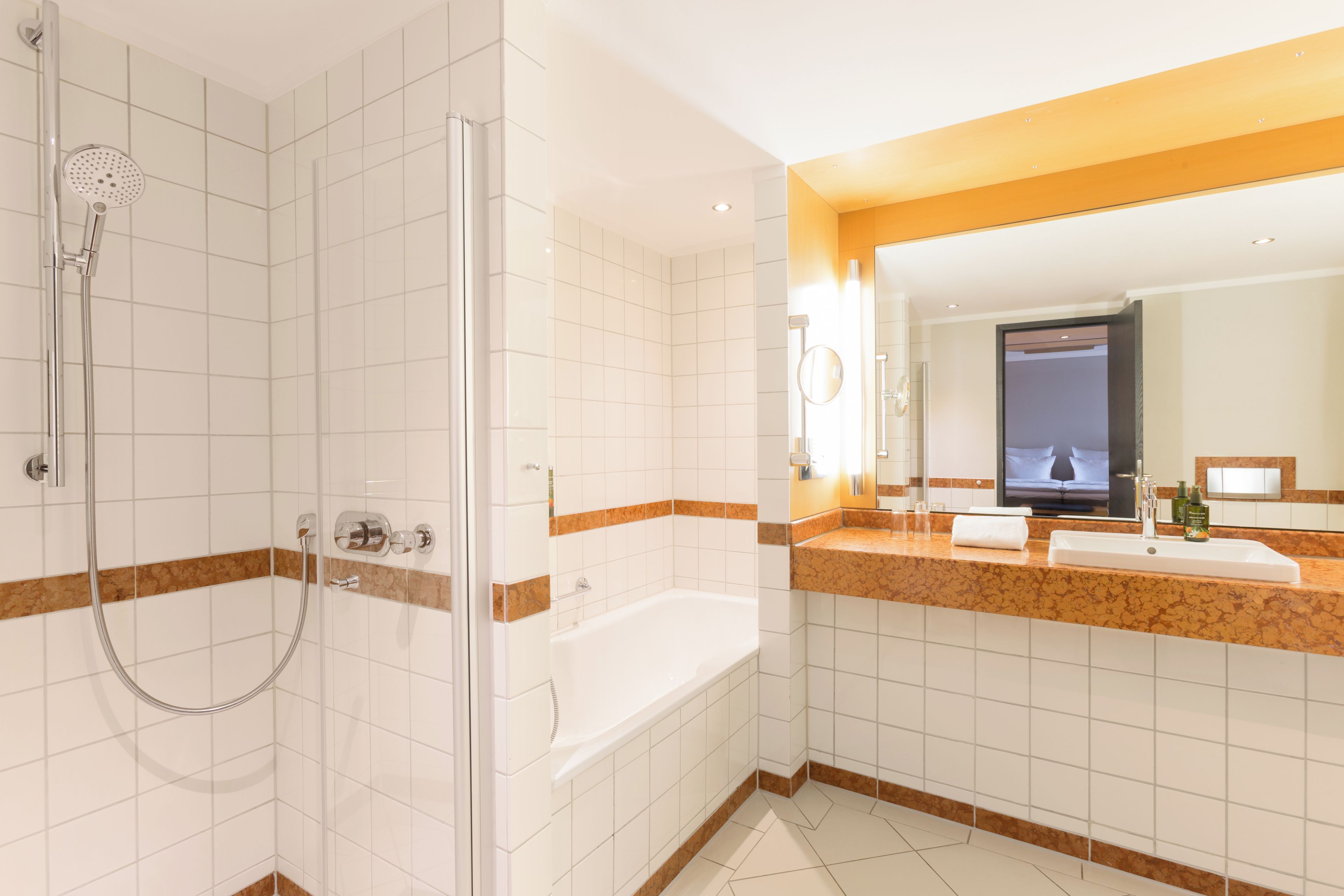 A modern bathroom with a glass-enclosed shower, a bathtub, and a vanity with a mirror.