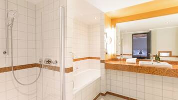 A modern bathroom with a glass-enclosed shower, a bathtub, and a vanity with a mirror.