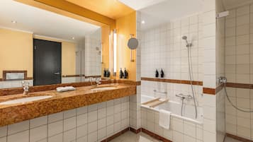A modern bathroom with a large mirror, two sinks, a bathtub, and a shower.