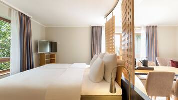 A hotel room with a large bed, a TV, a desk with a chair, and a view of the outdoors.