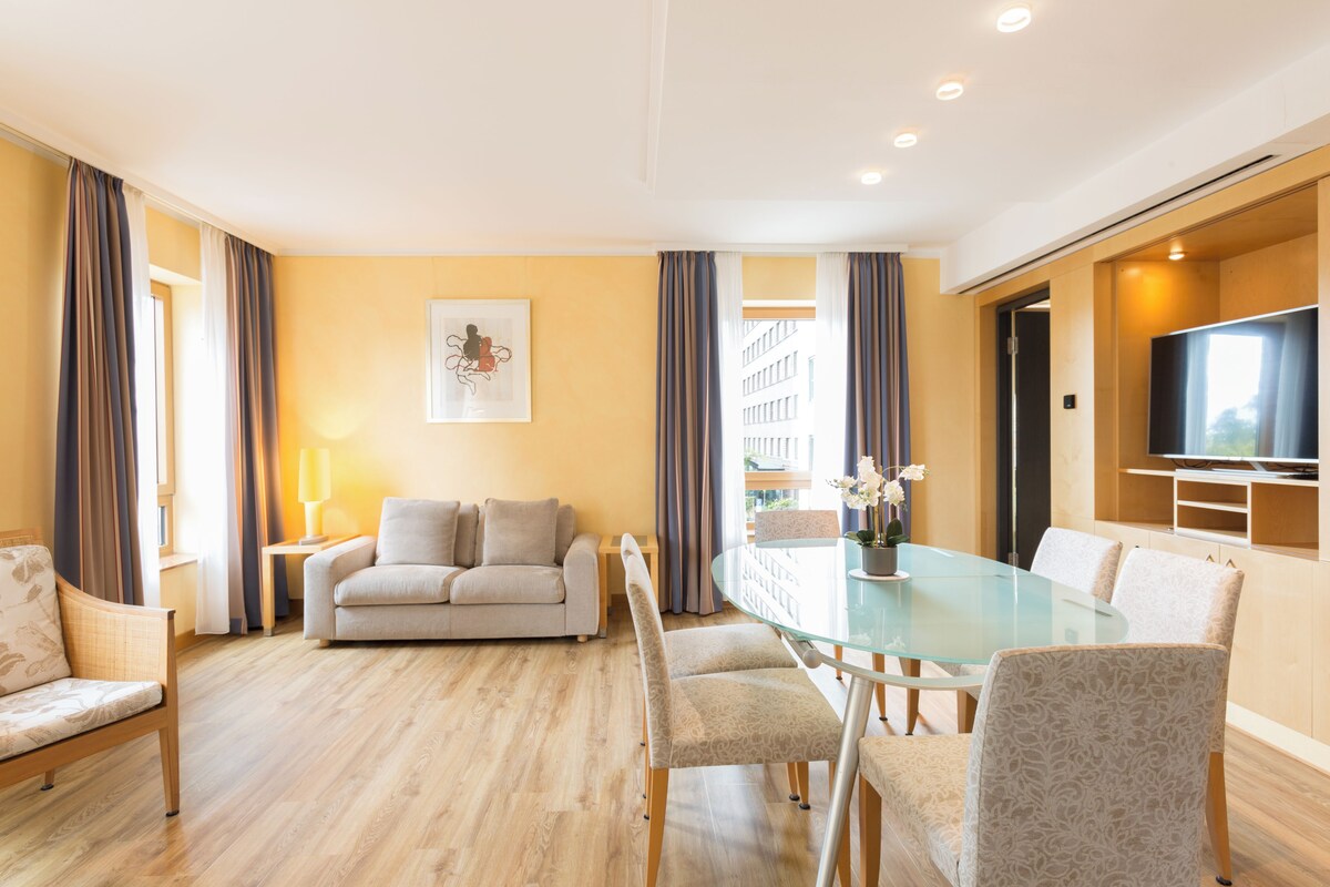 Una sala de estar moderna con un sofá, una mesa de comedor de vidrio y un televisor de pantalla plana.