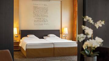 Une chambre d’hôtel avec un lit double, des lampes de chevet, un grand mur orné d’un mot écrit à la main et une plante orchidée en pot.