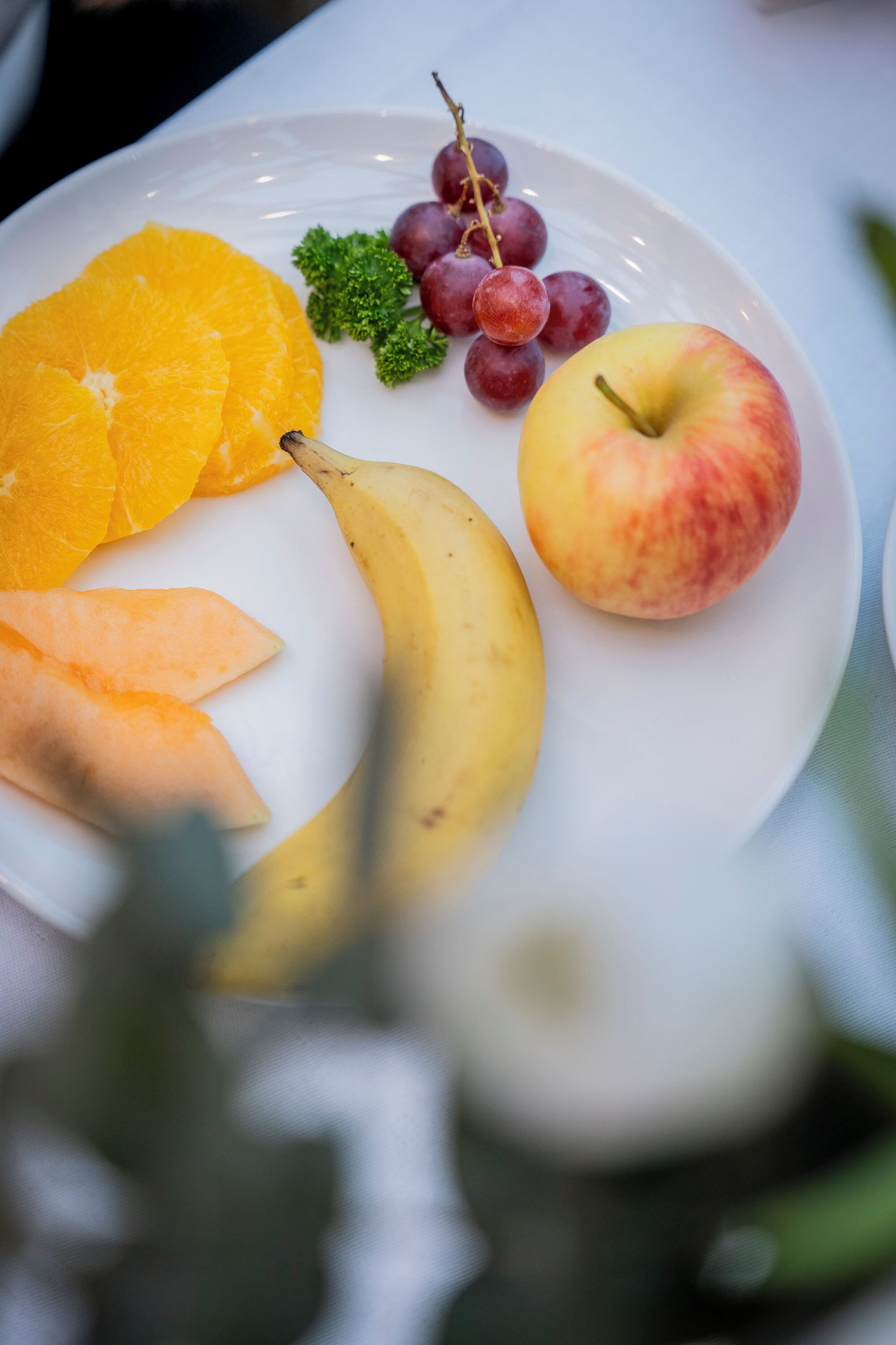 A plate with a banana, apple, grapes, and orange slices.
