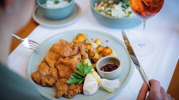 Une assiette de nourriture avec une fourchette et un couteau, un verre de boisson rouge et un saladier de salade.