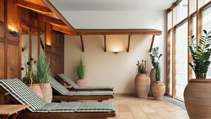 A spa area with wooden loungers, large potted plants, and a tiled floor.