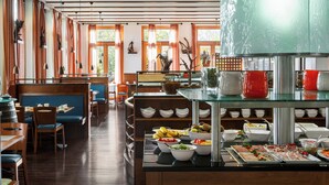 A restaurant with wooden furniture, a buffet with various food items, and large windows allowing natural light.