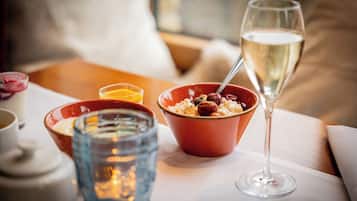 Una mesa de comedor con un tazón de cereal, una copa de vino blanco y una vela.