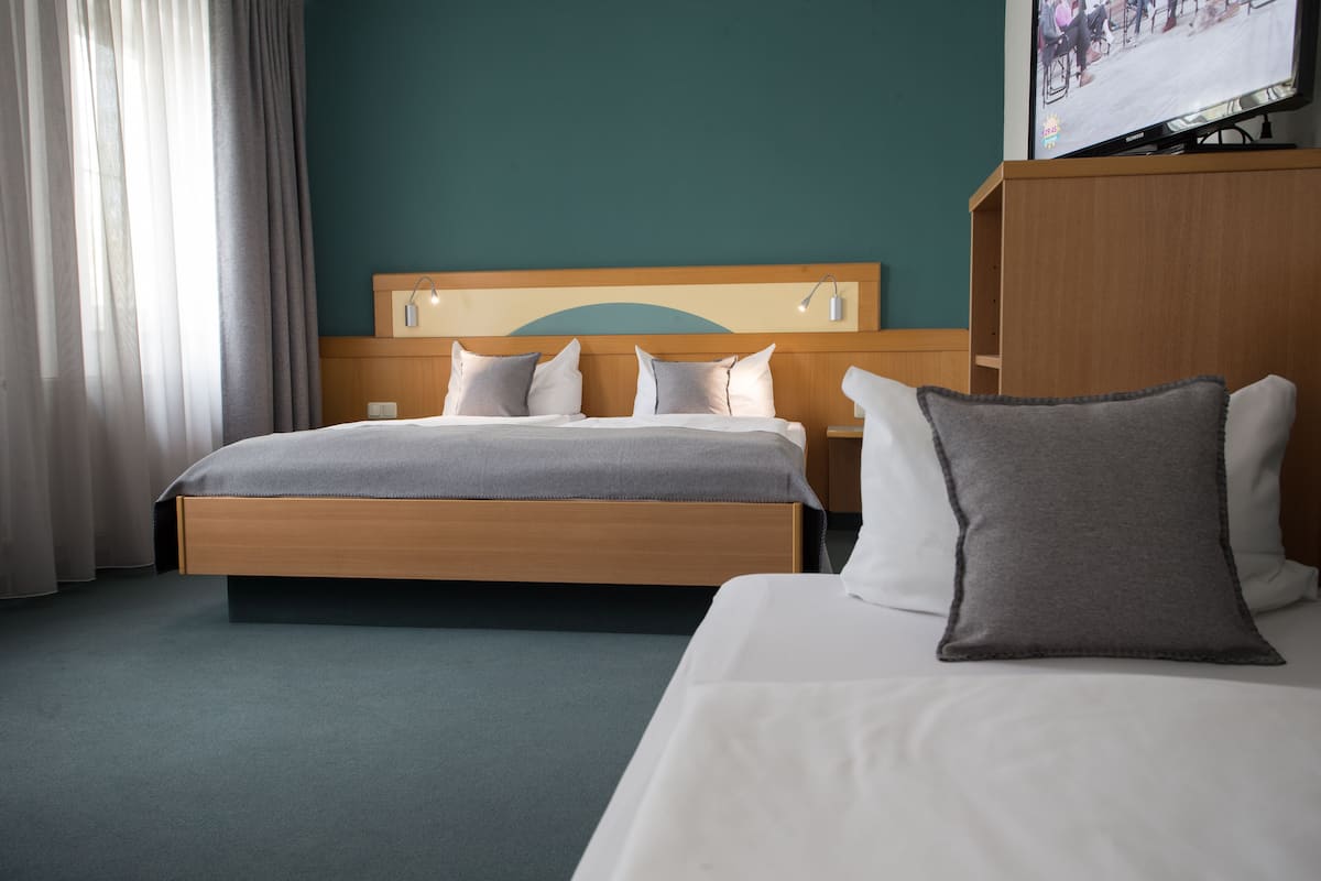 A hotel room with a bed, a nightstand, a TV, and a wardrobe.