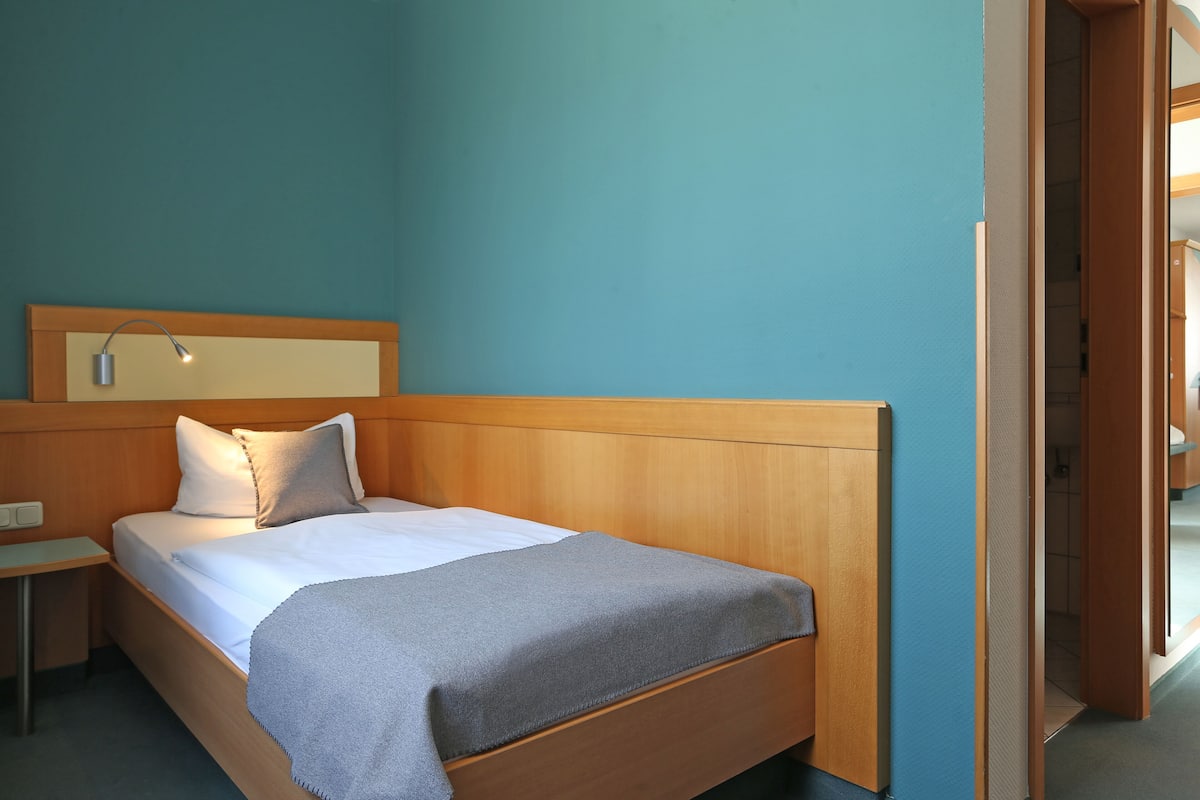 A neatly made bed with a wooden headboard, a bedside table, and a nightstand.