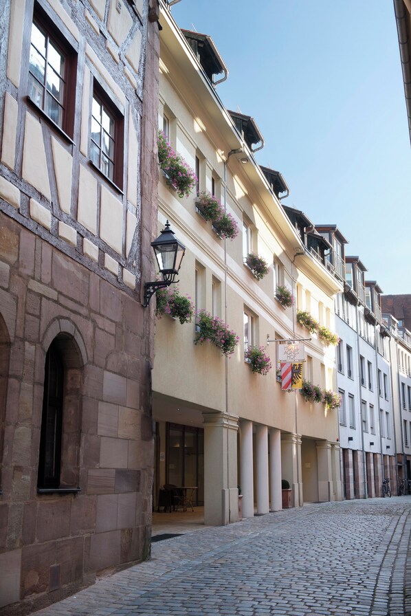 Experience the charm of this historic hotel, set amidst a traditional European building with a stone facade and flower-adorned windows.
