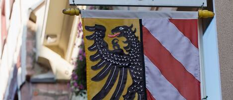 Une enseigne d’hôtel indiquant « HÔTEL AGNES HOF » et un drapeau orné d’un aigle noir.