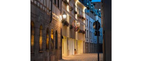 Calle adoquinada bordeada por edificios históricos con ventanas de arco y jardineras llenas de flores.