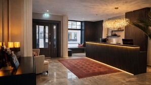 A modern hotel lobby with a reception desk, seating area, and a large window. - Hotel Bayrischer Hof (Heidelberg)