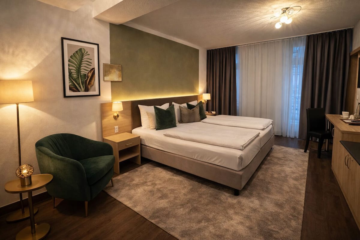 A hotel room with a large bed, a desk, a chair, a lamp, and a framed picture on the wall.
