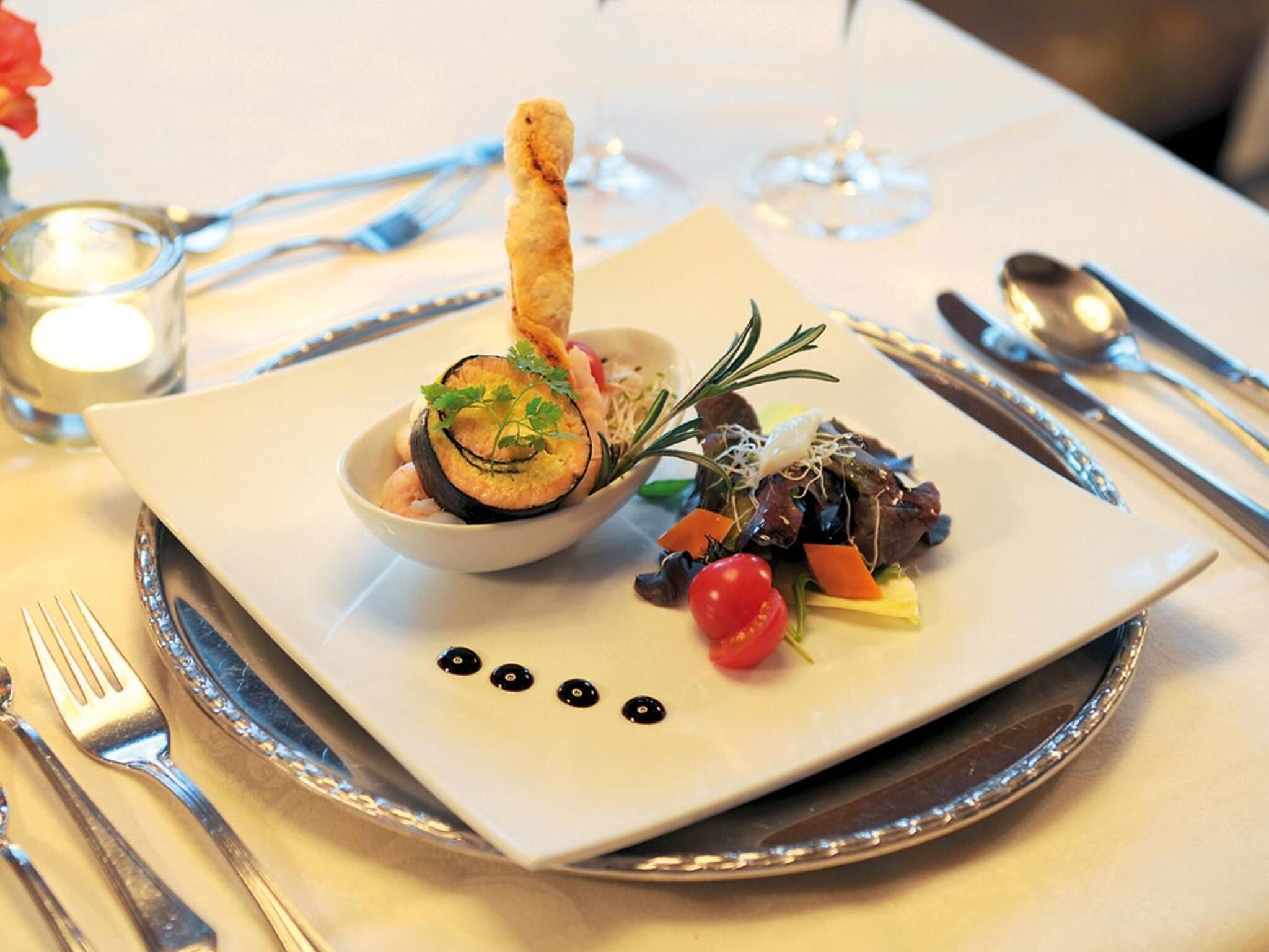 A plated meal with a variety of vegetables and a piece of bread, served on a white plate with a decorative border.