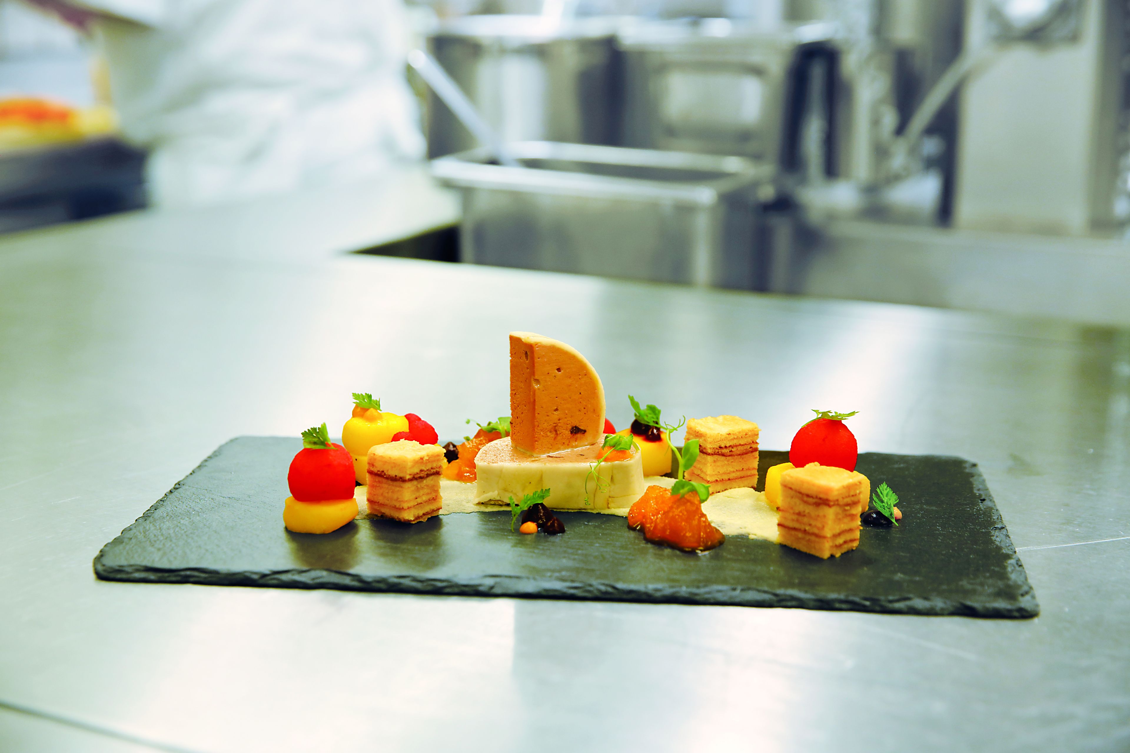 A dessert plate with various sweets and fruits on a slate serving board.
