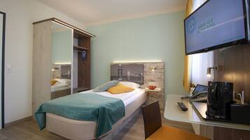 Una habitación de hotel con una cama, un escritorio con una computadora portátil, una cafetera y un televisor.