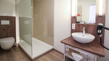 A modern bathroom with a glass-enclosed shower, a white sink, and a wooden vanity.