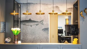 Una cocina moderna con un gran mural de peces, luces colgantes y un jarrón con flores blancas.