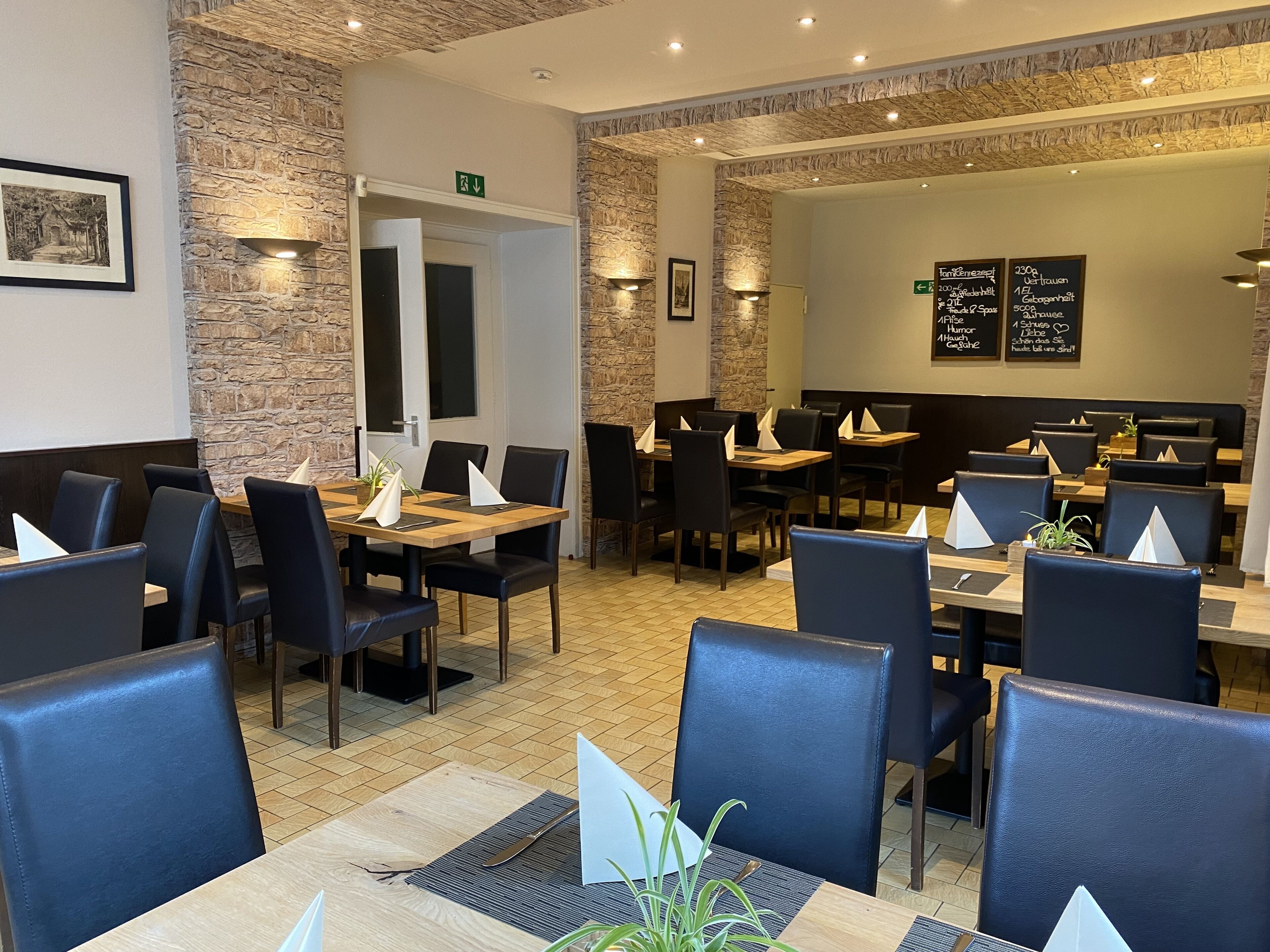 A restaurant with stone walls, wooden tables, and black chairs.