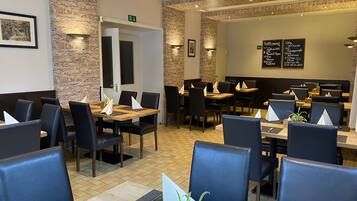A restaurant with stone walls, wooden tables, and black chairs.
