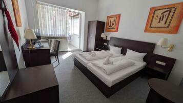Ein Hotelzimmer mit einem großen Bett, einem Schreibtisch, einem Sessel und zwei Bildern an der Wand.