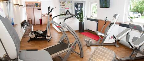 Un gimnasio con máquinas de cardio, una cinta de correr y una máquina de remo.
