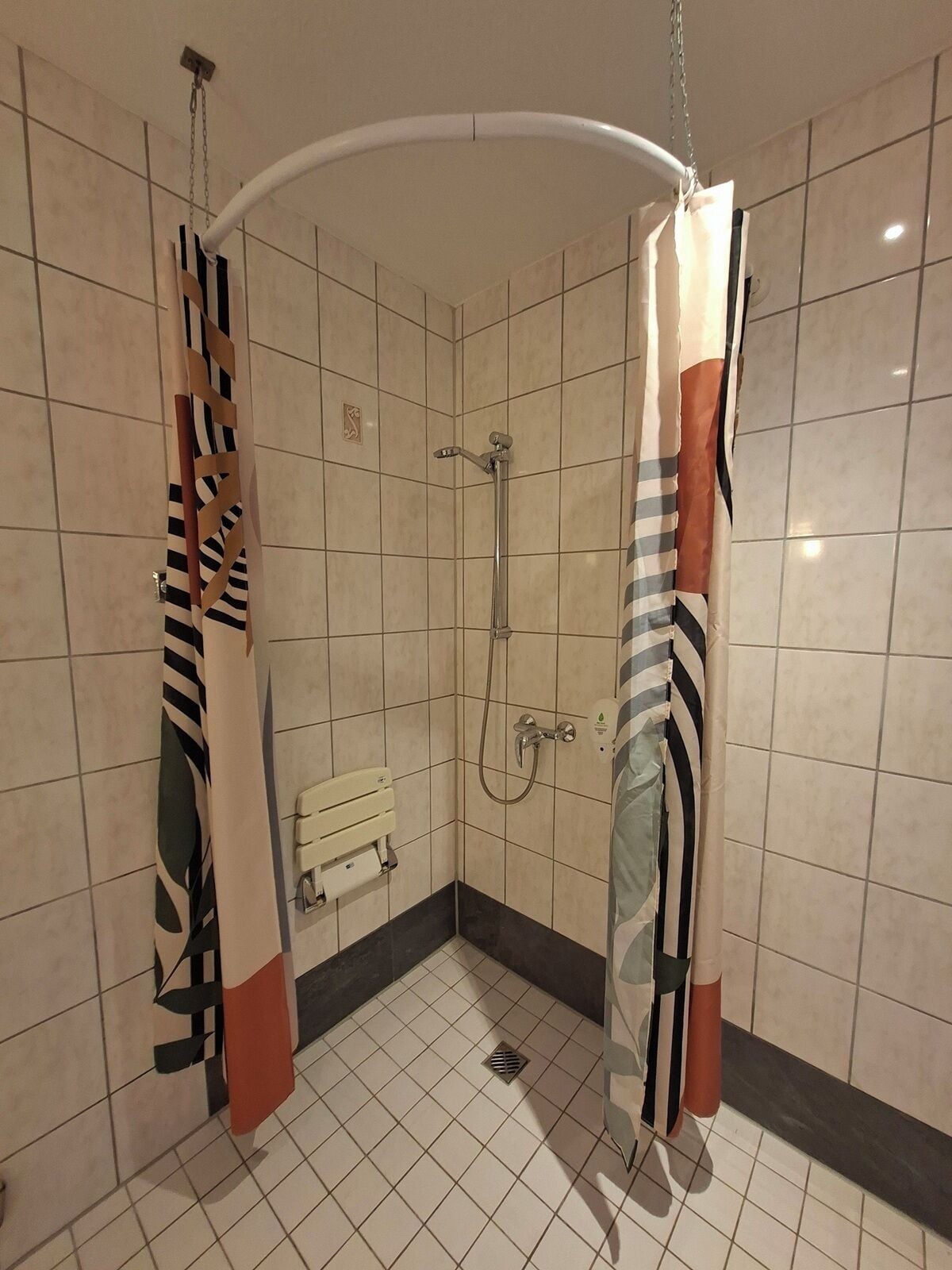 Un espace douche doté d’un pommeau de douche incurvé, d’un flexible de douche et d’un porte-serviettes.