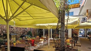 An outdoor seating area with yellow umbrellas, brick walls, and potted plants. - Hotel Sonne (Karlsruhe)