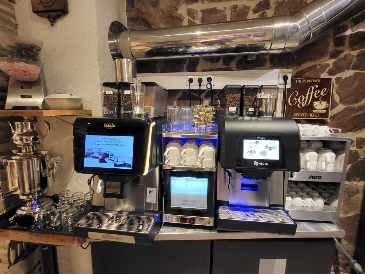 Ein Café mit mehreren Kaffeemaschinen, einer digitalen Anzeige und einem Schild mit der Aufschrift Kaffee.